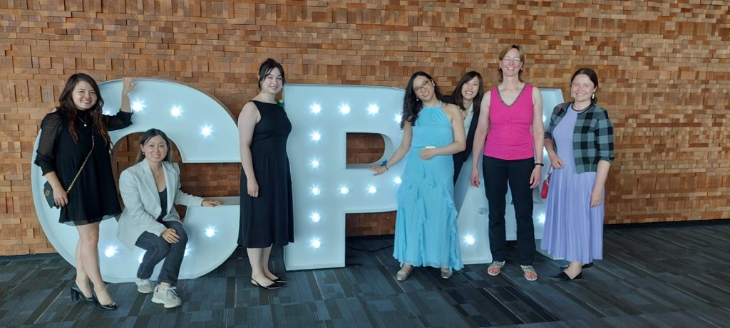 OAGBC financial staff pose in front of giant C-P-A letters at graduation event