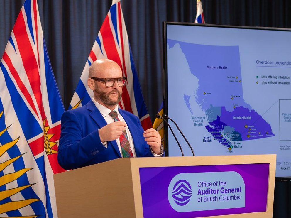 Auditor General, Michael A. Pickup, standing at a podium at a press conference.