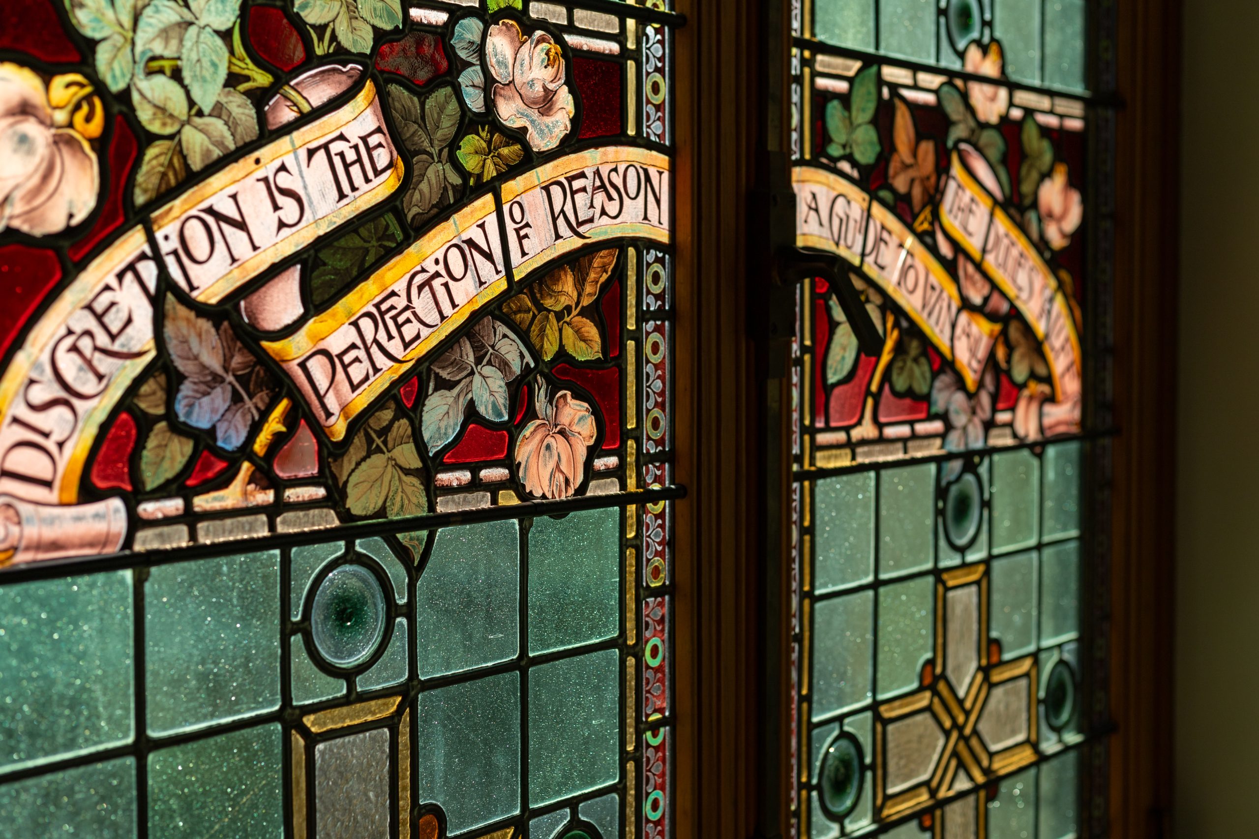 Stained glass window in the B.C. Parliament Buildings with message, "Discretion is the perfection of reason"