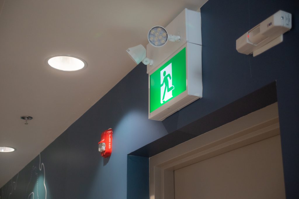 Accessible noise and strobe light fire alarm beside exit sign.